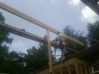 Carpenter setting a ridge beam over a new addition frame — Ice Dam Removal by Roofing Brothers in Broomes Island