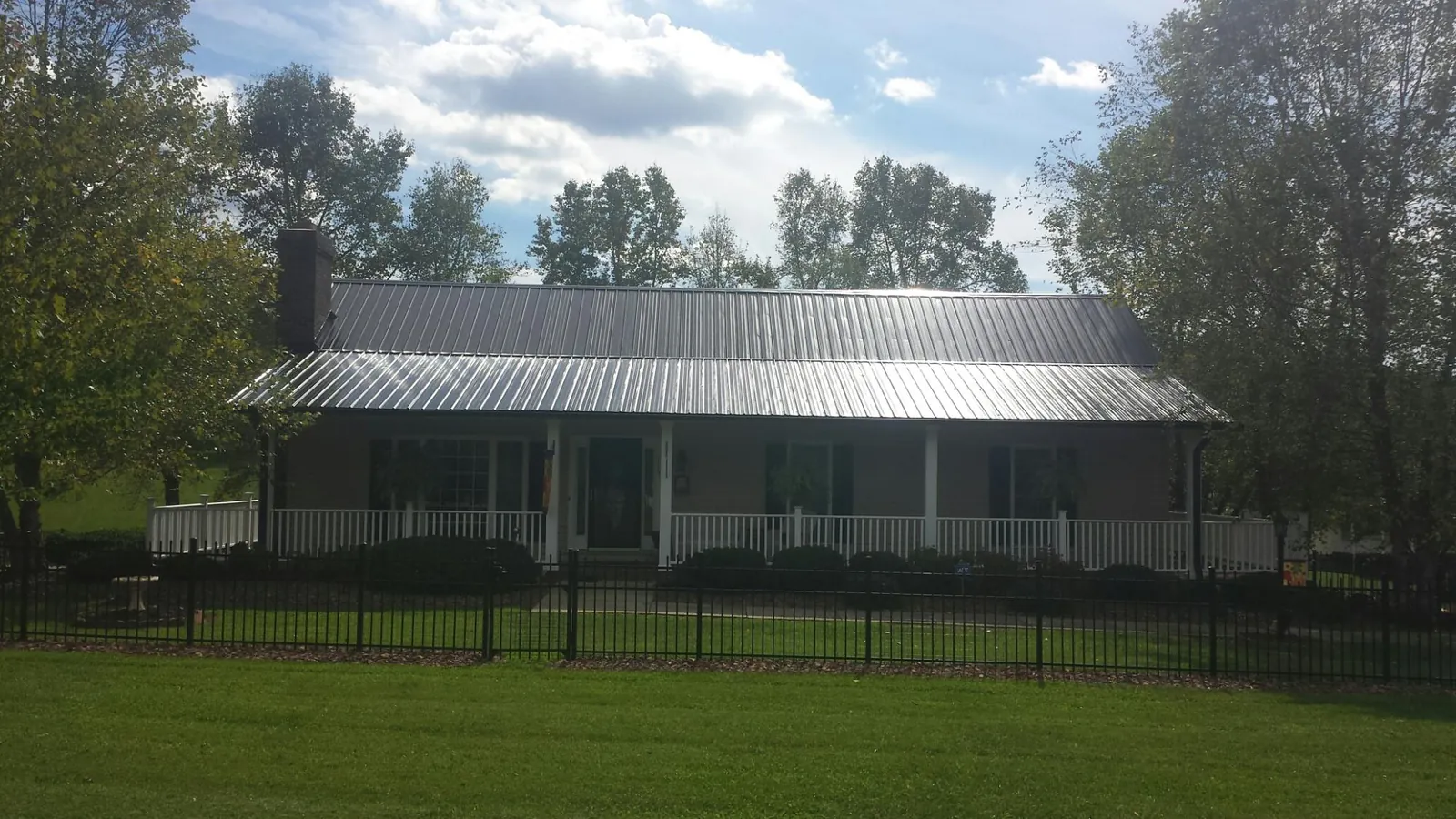 Gray metal roof on a brick ranch with a full width front porch — Gutter Guard Installation work by our crew in Broomes Island