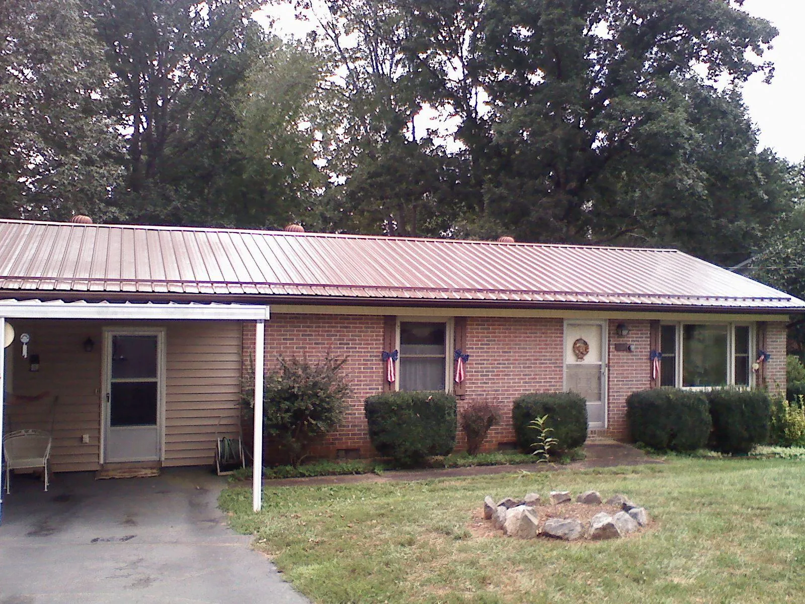 Bronze metal roof and carport on a brick ranch home — Roof Repair work by our crew in Broomes Island