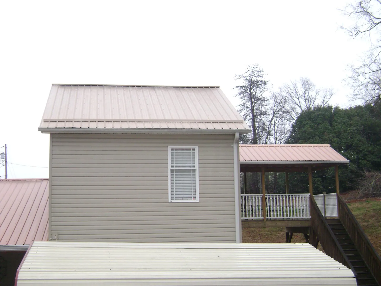 Tan metal roofs on a two story addition and attached porch, from a Roof Replacement job in Broomes Island