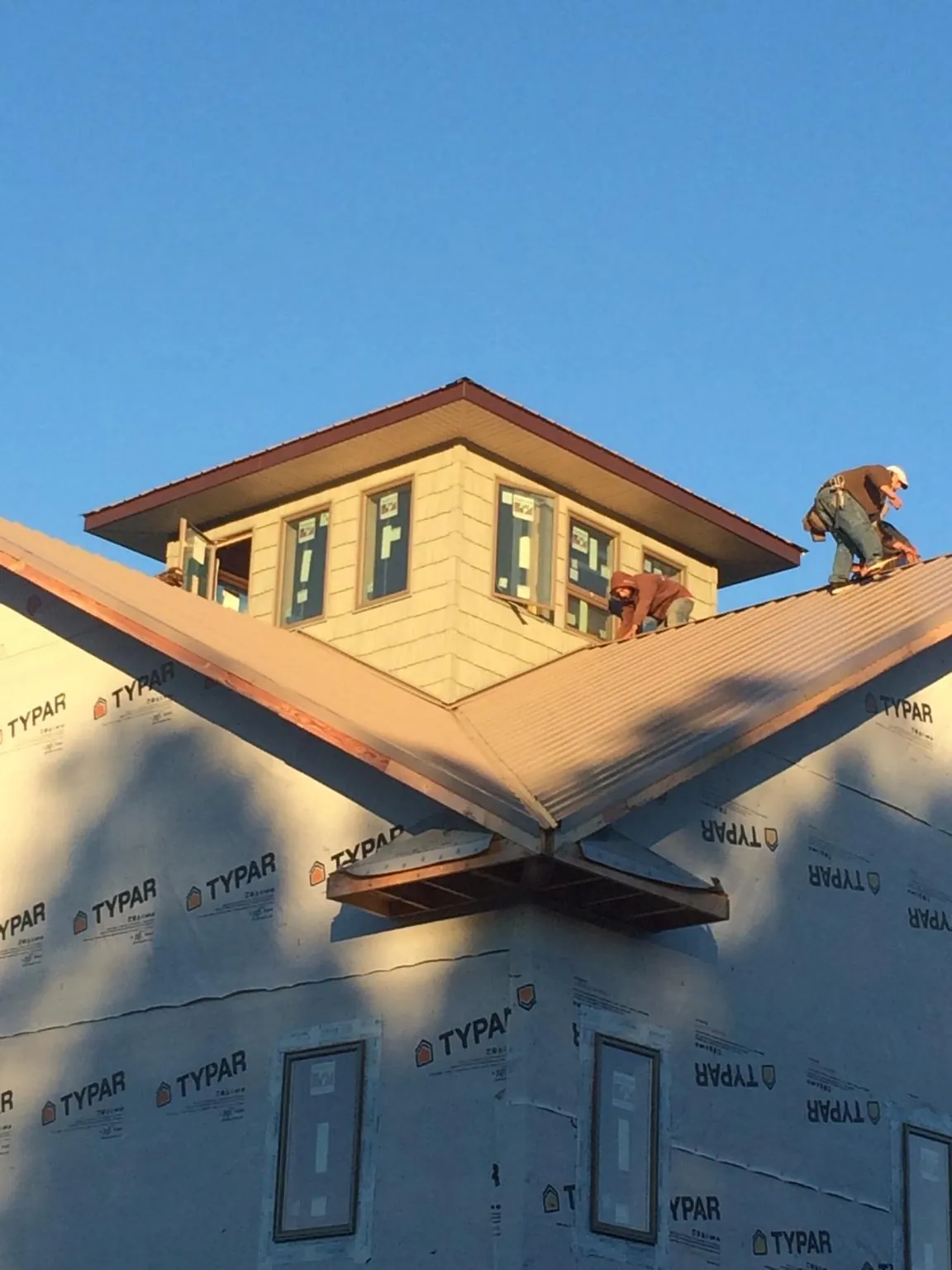 Roofers working around a rooftop cupola on a new metal roof at sunset — Roof Waterproofing in Broomes Island by Roofing Brothers
